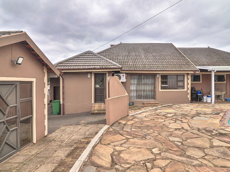 Rear exterior view featuring a stone-paved patio area, swimming pool, and access to the main dwelling with security gates and tiled roofing.