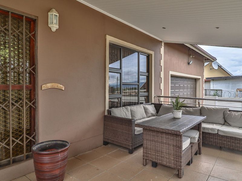 A covered patio area featuring tiled flooring, recessed lighting, and a security gate, providing a functional outdoor space adjacent to the garage.