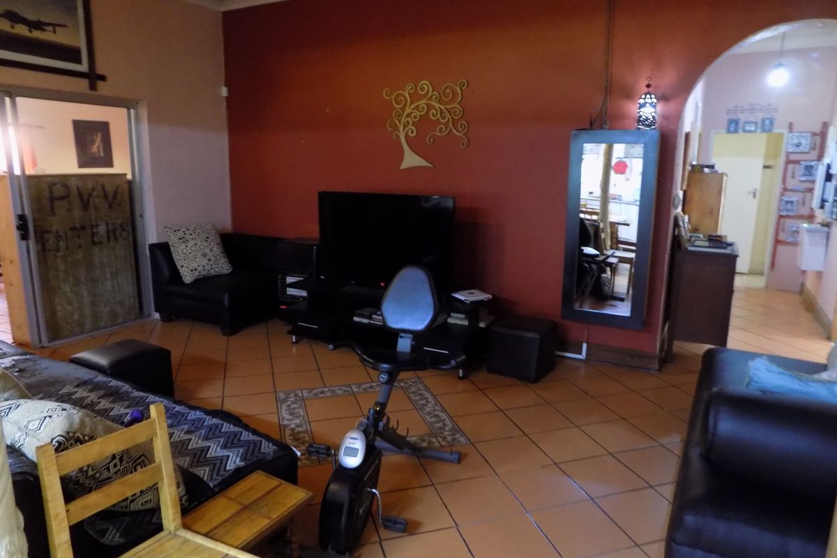A living room featuring terracotta floor tiles and an arched entryway leading to an adjacent space.
