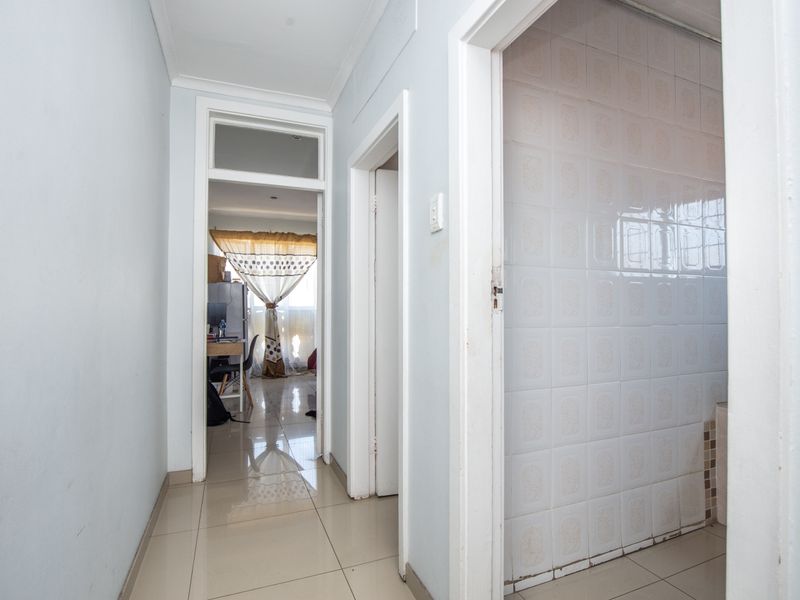 A clean, tiled hallway providing access to adjacent rooms, featuring neutral wall tones and standard architectural finishes.