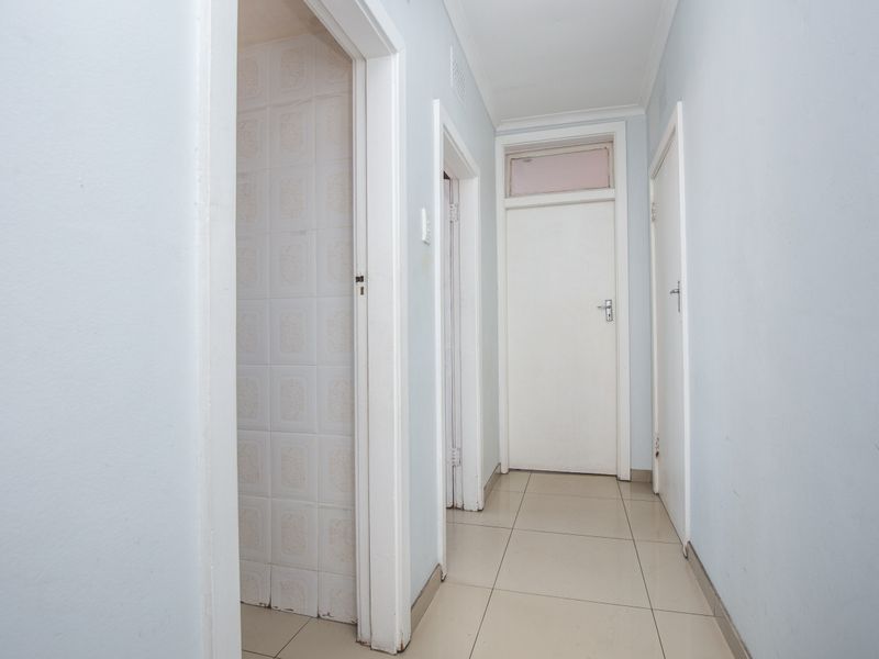 A functional apartment hallway featuring tiled flooring and multiple internal access doors.