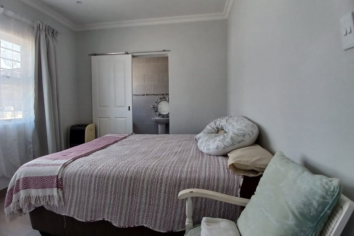 A bedroom featuring neutral walls, recessed lighting, and a sliding door providing access to an en-suite bathroom.