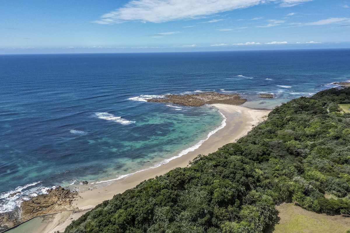 An aerial view of the coastal landscape, showcasing the pristine beach, turquoise ocean waters, and surrounding natural vegetation.