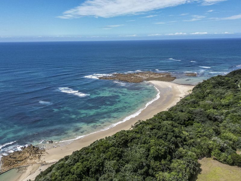 An aerial view of the coastal landscape, showcasing the pristine beach, turquoise ocean waters, and surrounding natural vegetation.