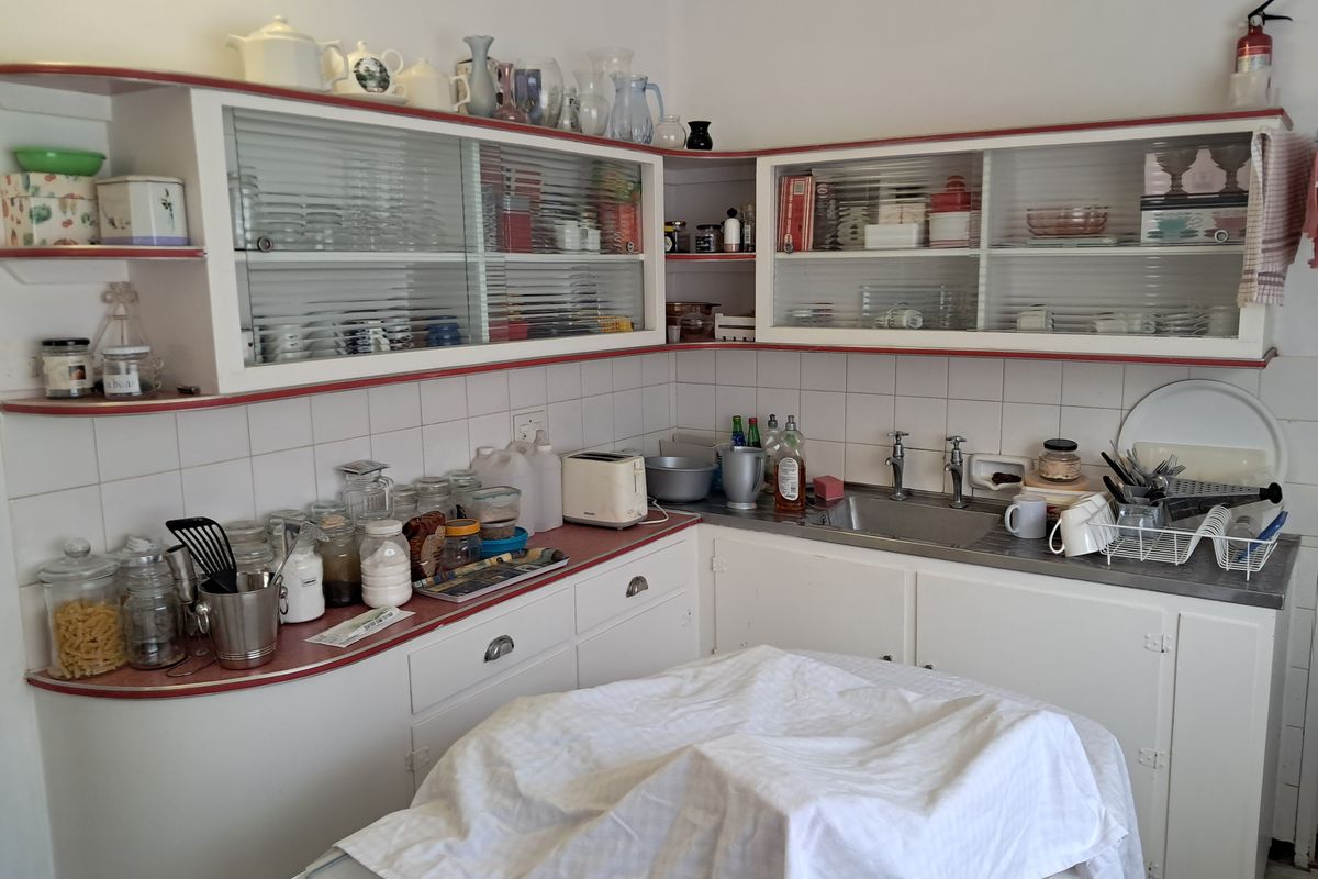 A functional kitchen area featuring built-in cabinetry, a stainless steel sink, and tiled splashbacks, offering a practical layout for food preparation and storage.