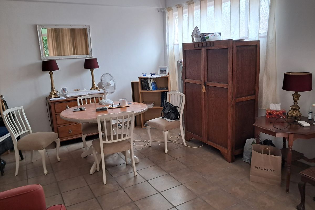 A multi-purpose living area featuring tiled flooring and large windows, offering a functional space suitable for dining or casual relaxation.