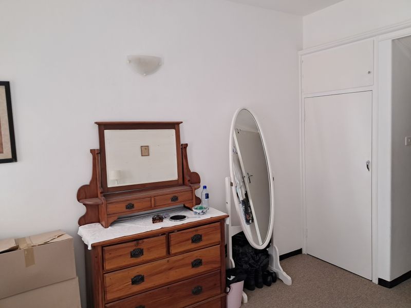 A bedroom featuring neutral walls, carpeted flooring, and a built-in cupboard with overhead storage.