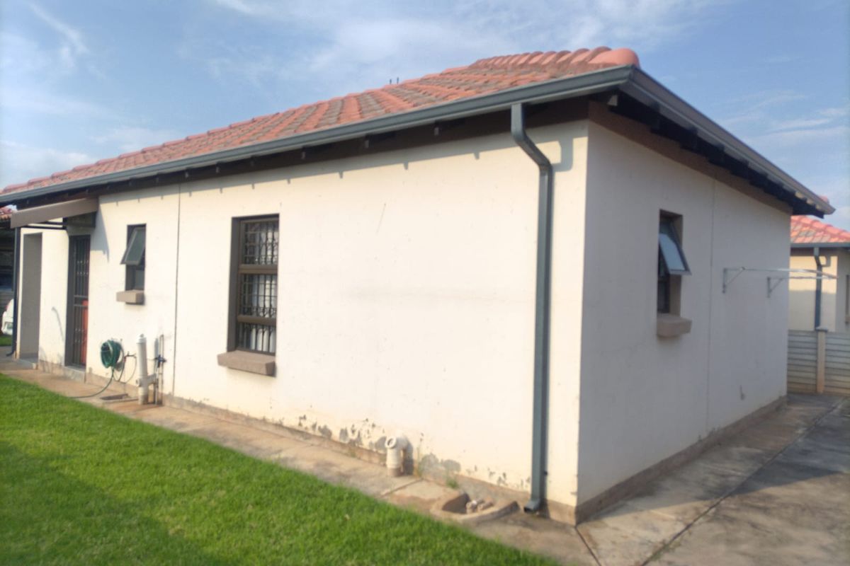 Rear exterior view of the house featuring terracotta roof tiles, gutters, and security bars on the windows.