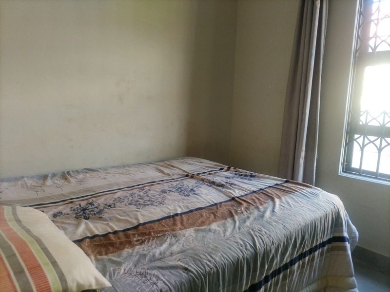 A bedroom featuring a window with security burglar bars and neutral wall finishes, requiring minor cosmetic updates.