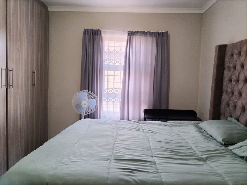A functional bedroom featuring a built-in wardrobe and a window fitted with a security gate.