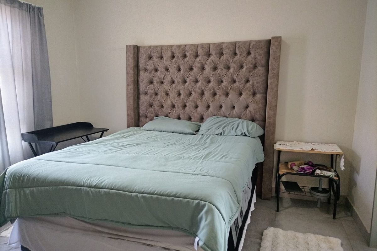 A functional bedroom featuring tiled flooring and neutral wall finishes, providing a clean and simple space for rest.
