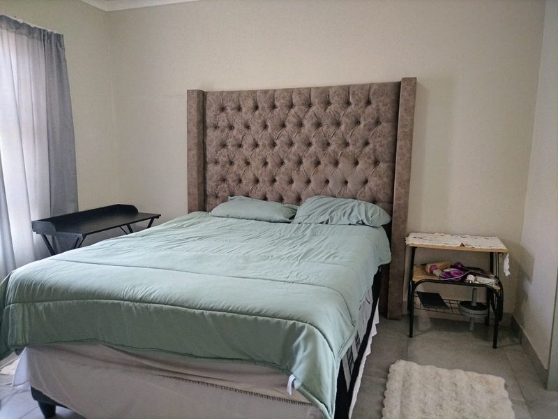 A functional bedroom featuring tiled flooring and neutral wall finishes, providing a clean and simple space for rest.