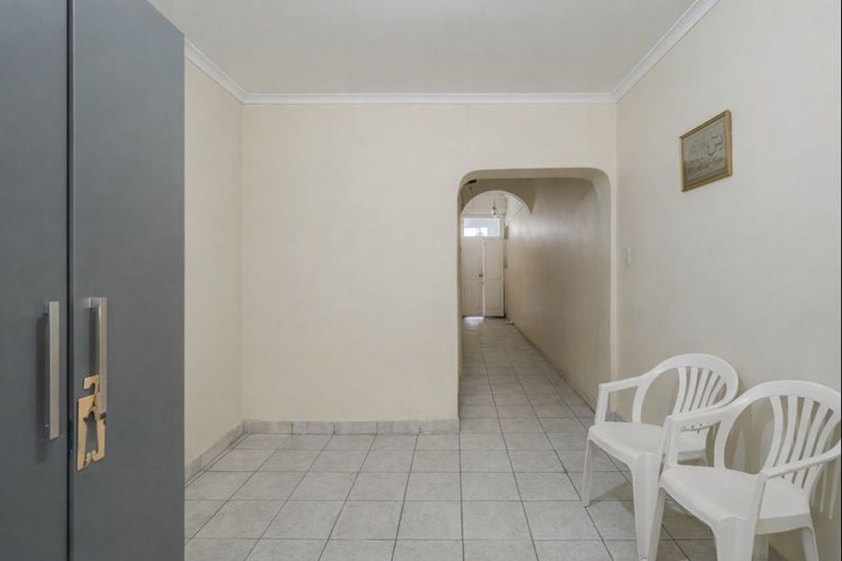 A neutral hallway featuring tiled flooring and an arched transition leading to an adjacent area of the home.