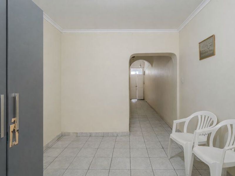 A neutral hallway featuring tiled flooring and an arched transition leading to an adjacent area of the home.