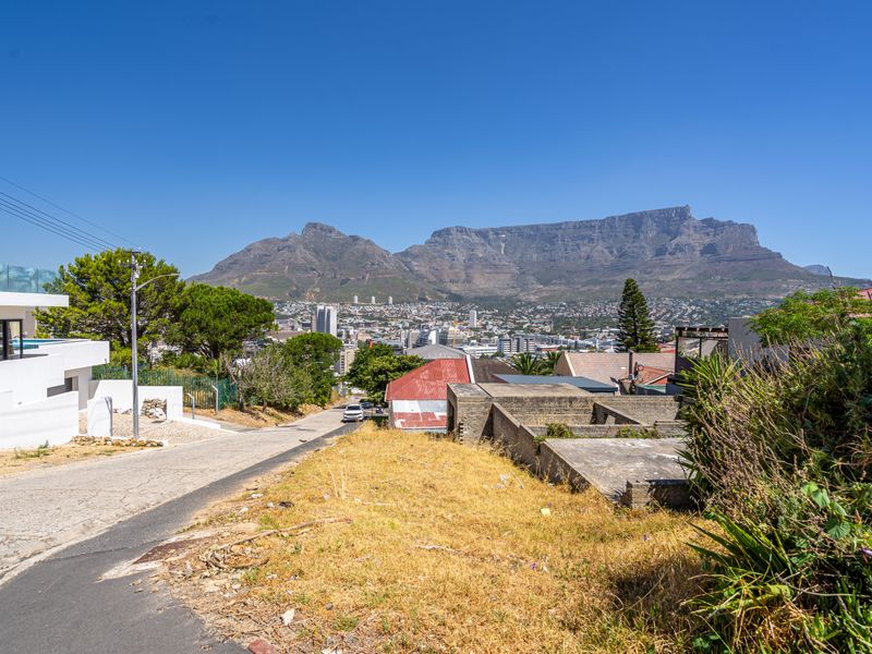 A scenic elevated view overlooking the neighborhood with Table Mountain in the background, featuring a paved driveway and surrounding residential landscape.