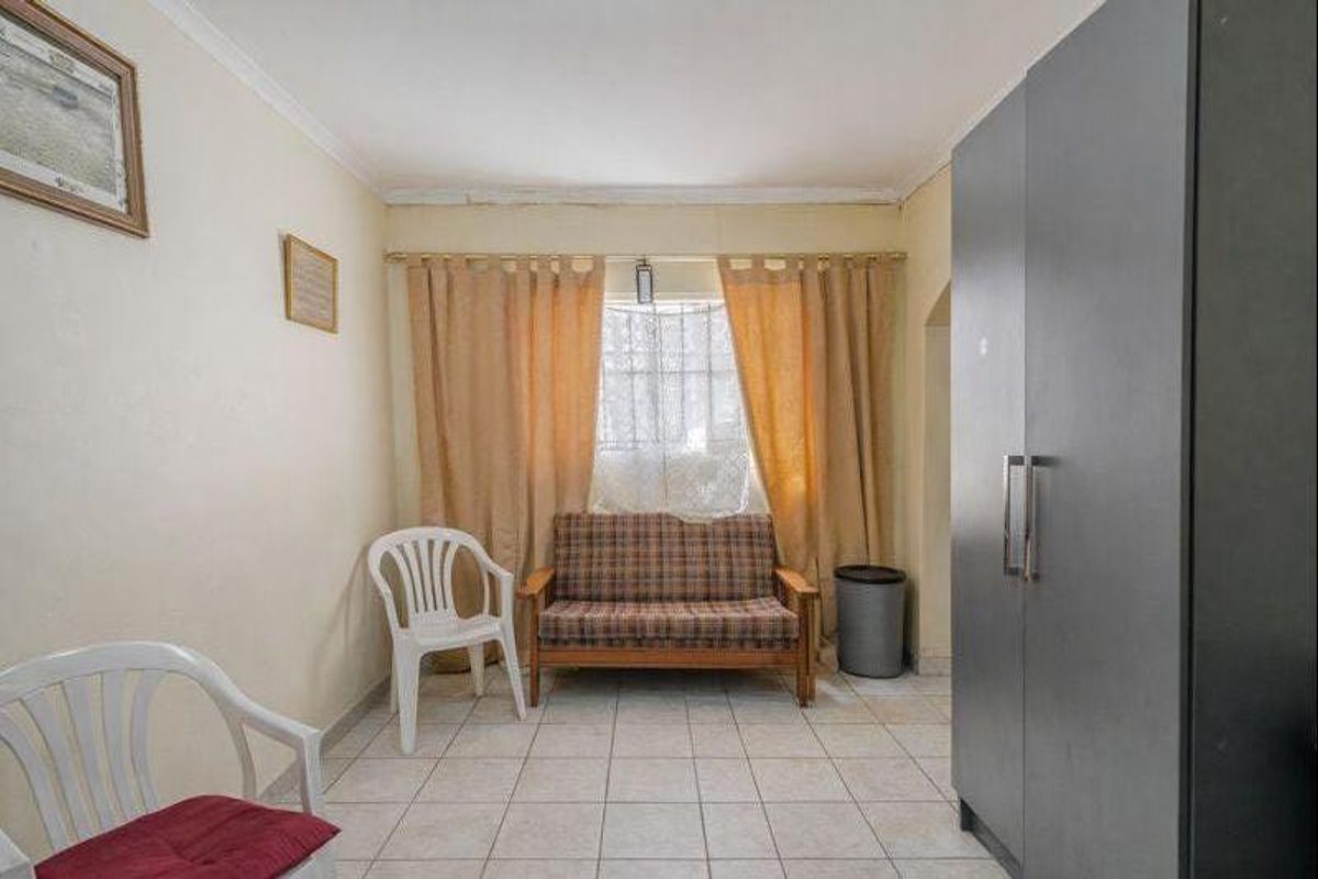 A bedroom featuring tiled flooring and a built-in wardrobe, offering a functional space with potential for cosmetic updates.