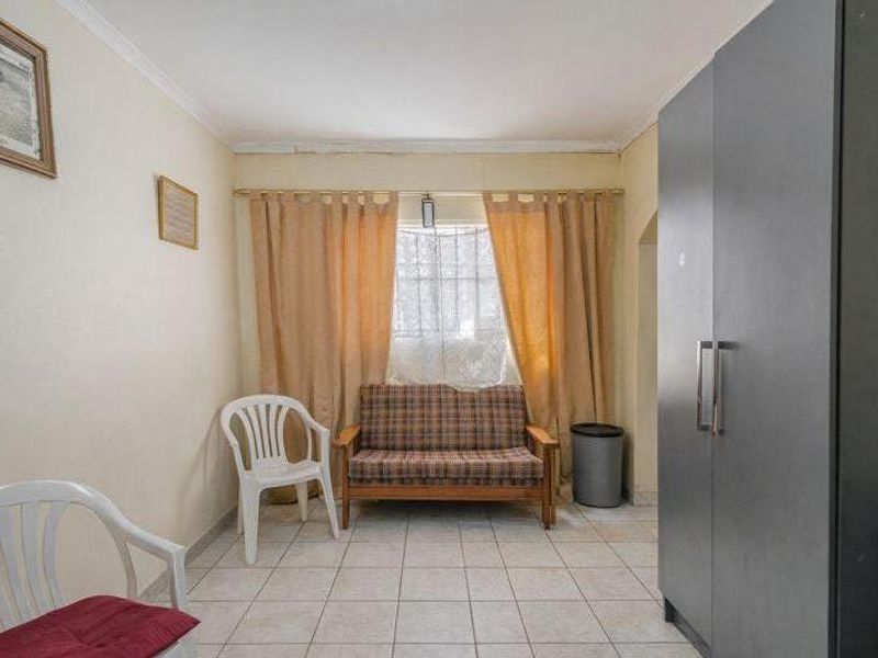 A bedroom featuring tiled flooring and a built-in wardrobe, offering a functional space with potential for cosmetic updates.