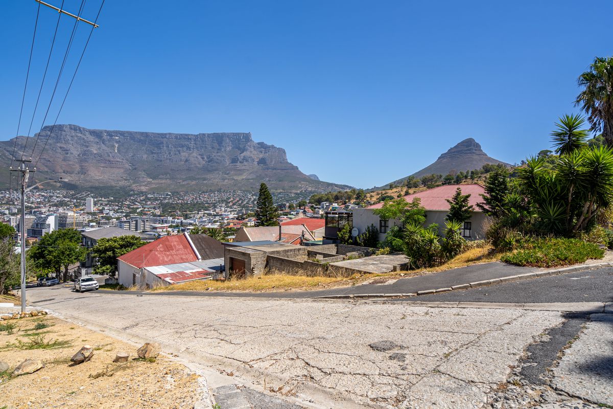 A scenic elevated view overlooking the city with prominent mountain vistas in the background.