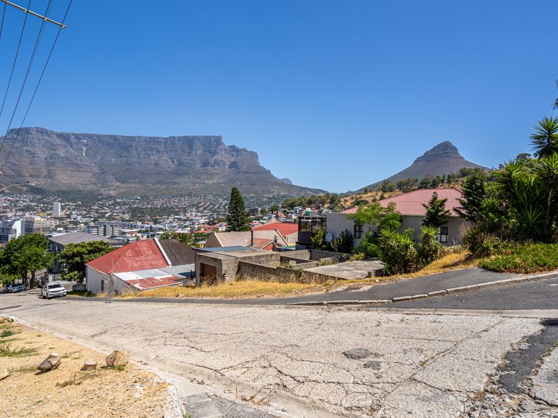 A scenic elevated view overlooking the city with prominent mountain vistas in the background.
