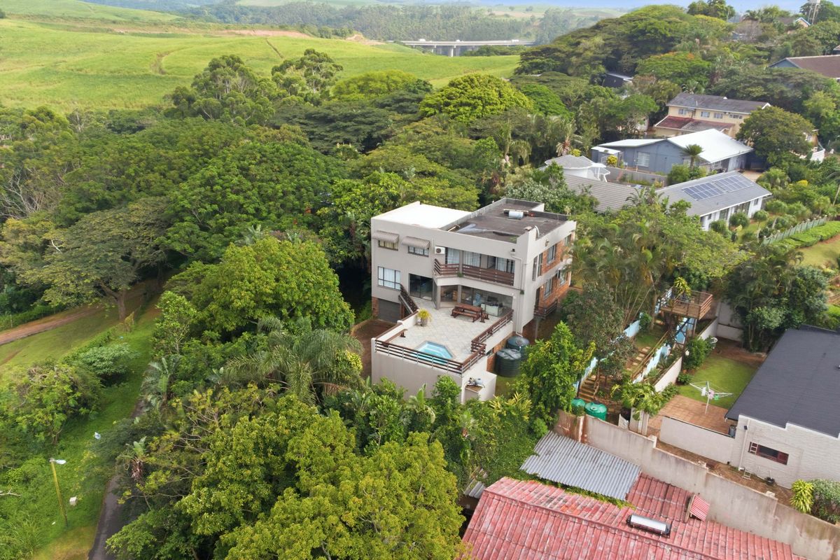 Aerial view of a multi-level residential property featuring a swimming pool, spacious terrace, and lush surrounding greenery in a scenic landscape.