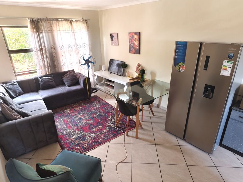 Open plan living area featuring tiled flooring and large window, providing a functional space for lounge and dining arrangements.