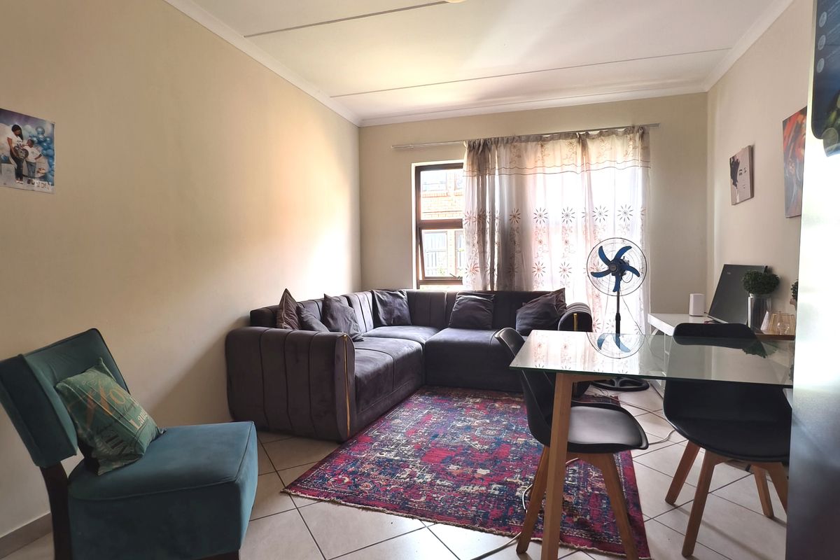 A living room area featuring tiled flooring and a coved ceiling, providing a functional space for relaxation and dining.