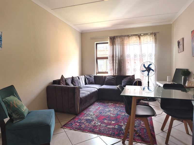 A living room area featuring tiled flooring and a coved ceiling, providing a functional space for relaxation and dining.