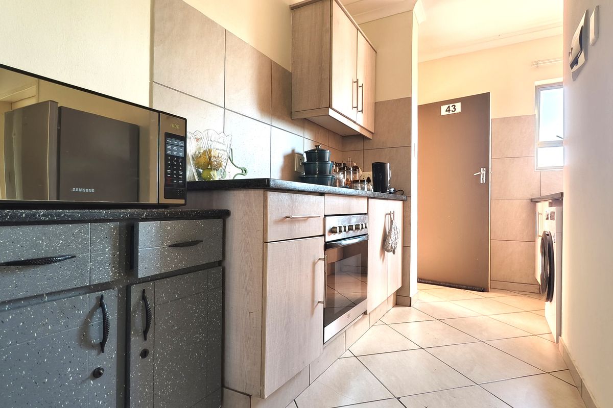 A functional kitchen featuring built-in cabinetry, laminate countertops, a built-in oven, and tiled flooring with integrated laundry space.