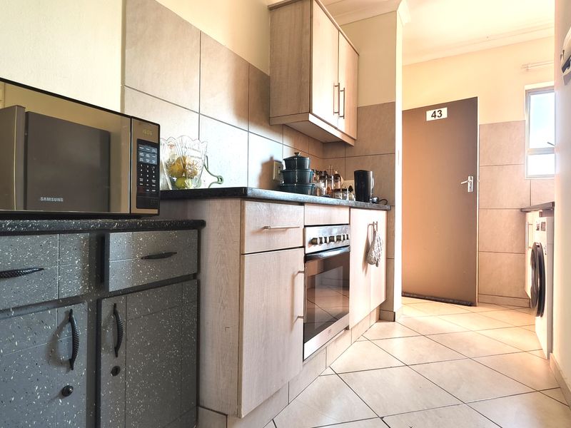 A functional kitchen featuring built-in cabinetry, laminate countertops, a built-in oven, and tiled flooring with integrated laundry space.