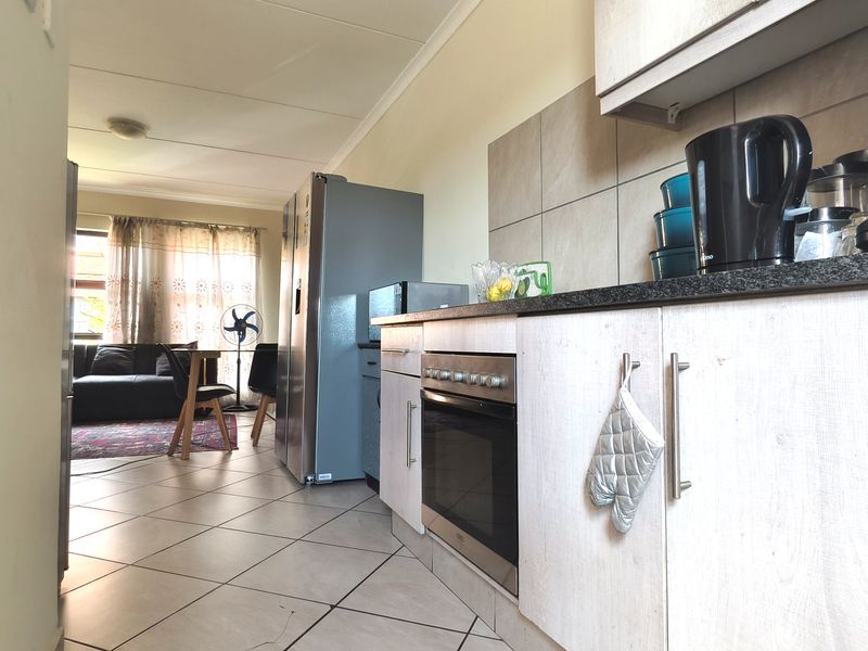 Open-plan kitchen and living area featuring tiled flooring, built-in cabinetry, and a functional oven, creating a cohesive and practical living space.