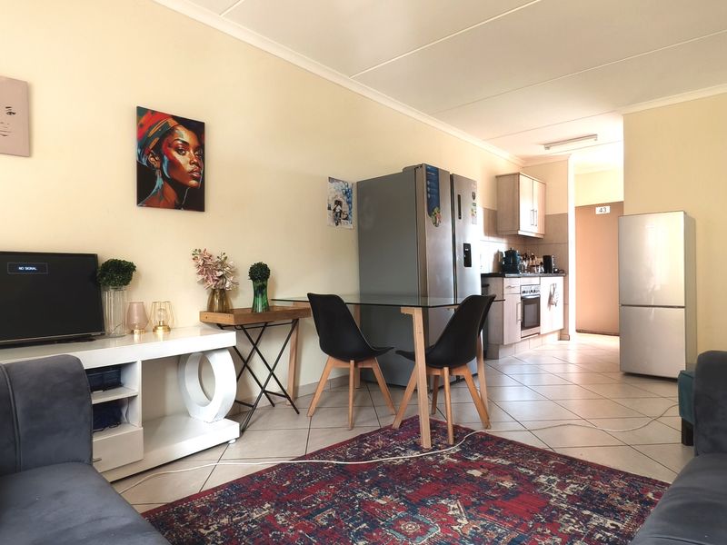 An open-plan living and kitchen area featuring tiled flooring and functional built-in cabinetry, offering a versatile space for daily living and dining.