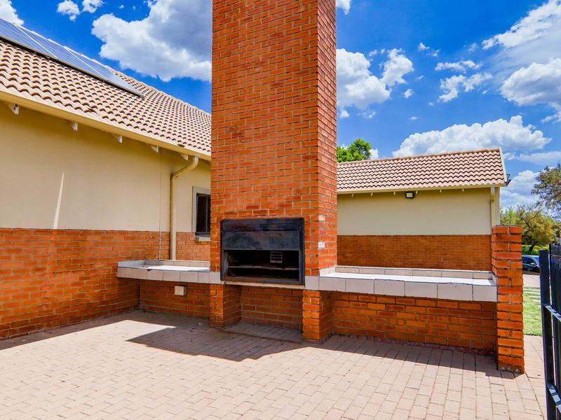 Outdoor patio area featuring a large built-in brick braai with tiled prep surfaces and paved flooring, ideal for outdoor entertaining.