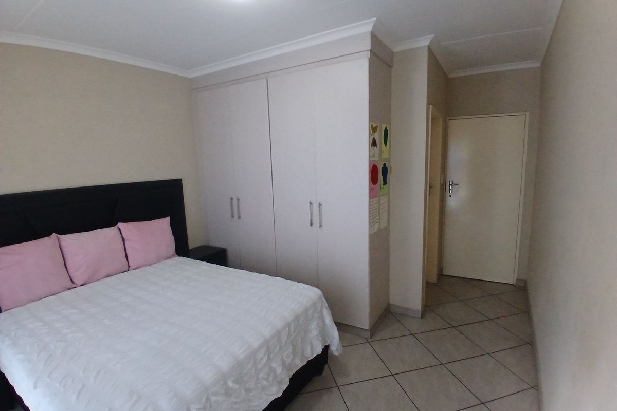 A bedroom featuring built-in cupboards, tiled flooring, and coved ceiling details.