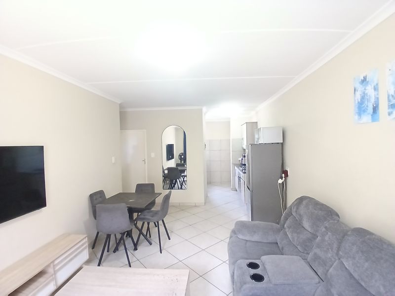 An open-plan living and kitchen area featuring tiled flooring and neutral wall finishes, providing a functional and connected layout for daily living.