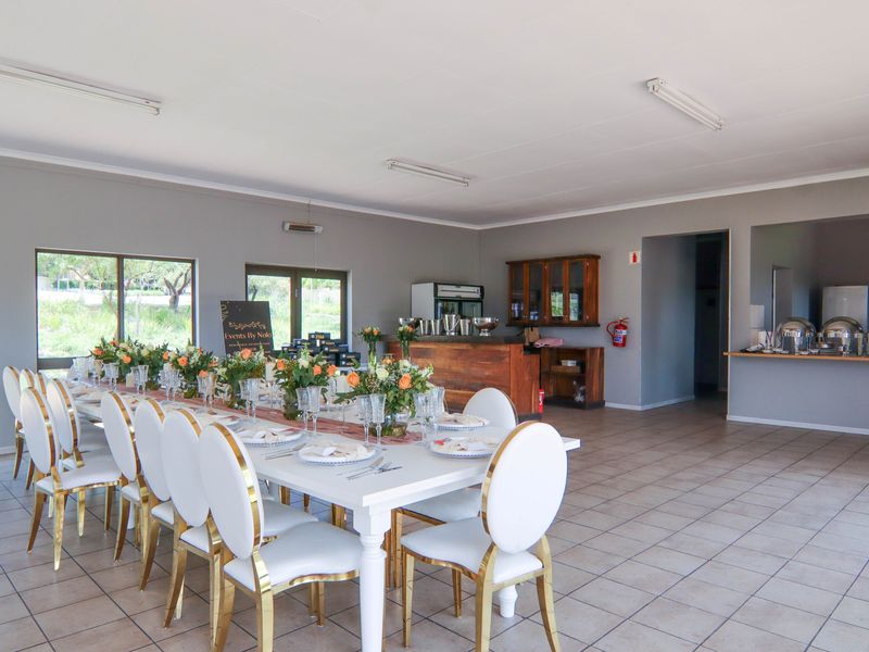 Spacious clubhouse area featuring tiled flooring, a built-in wooden bar counter, and a dedicated serving station, suitable for events and gatherings.