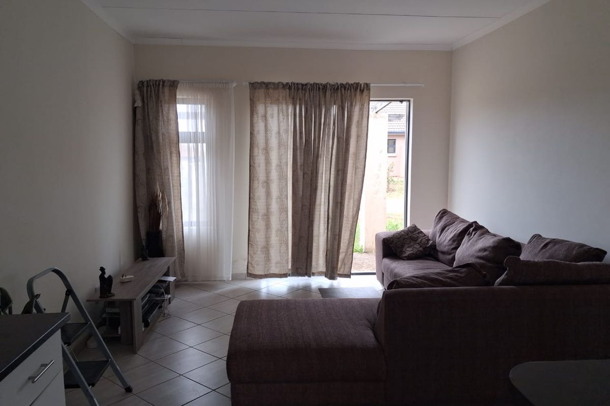 A living room featuring tiled flooring and sliding glass doors that provide access to the exterior.