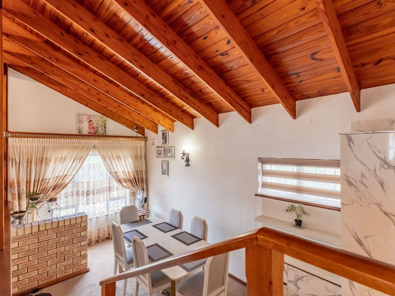 Dining area featuring a vaulted timber beam ceiling, brick partition wall, and built-in cabinetry, offering a warm and rustic aesthetic.