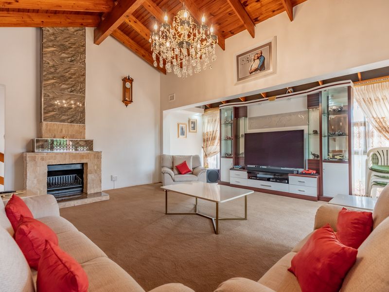 Spacious living room featuring a vaulted timber ceiling, a stone fireplace, and integrated built-in display cabinetry.