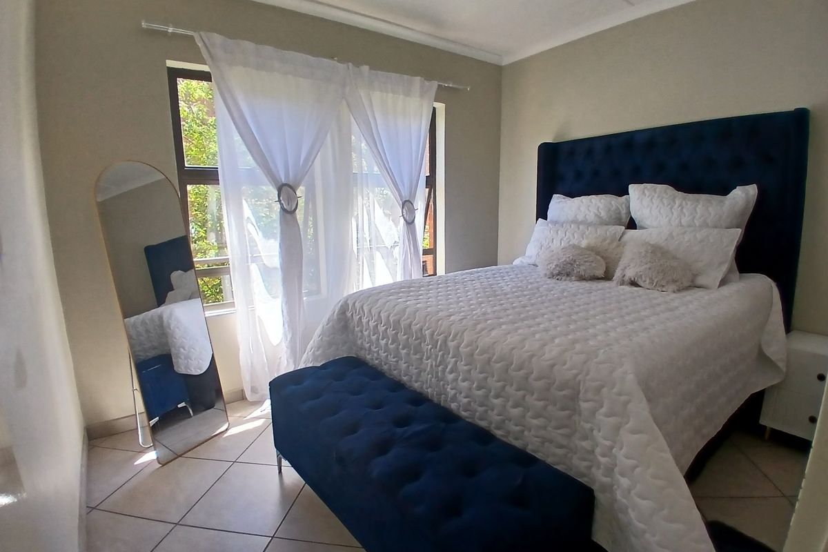 A well-maintained bedroom featuring neutral tiled flooring and a large window with natural light, providing a comfortable and functional living space.