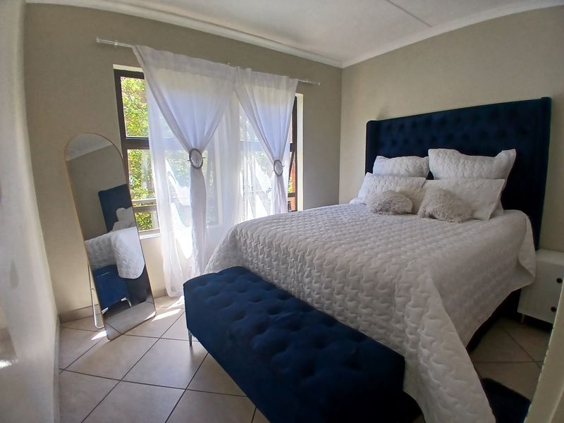 A well-maintained bedroom featuring neutral tiled flooring and a large window with natural light, providing a comfortable and functional living space.