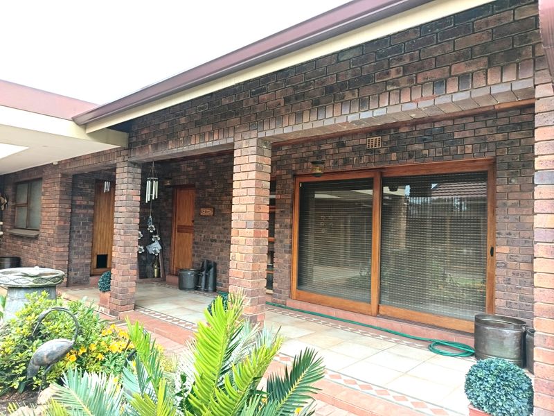 A covered patio area featuring exposed brick pillars, tiled flooring, and large wooden sliding doors providing access to the home interior.