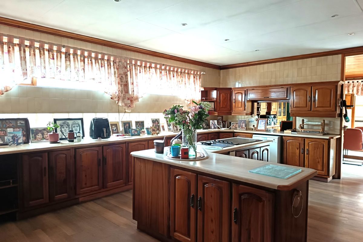 Spacious kitchen featuring traditional timber cabinetry, a central island, integrated cooktop, and ample counter space with neutral wall tiling.