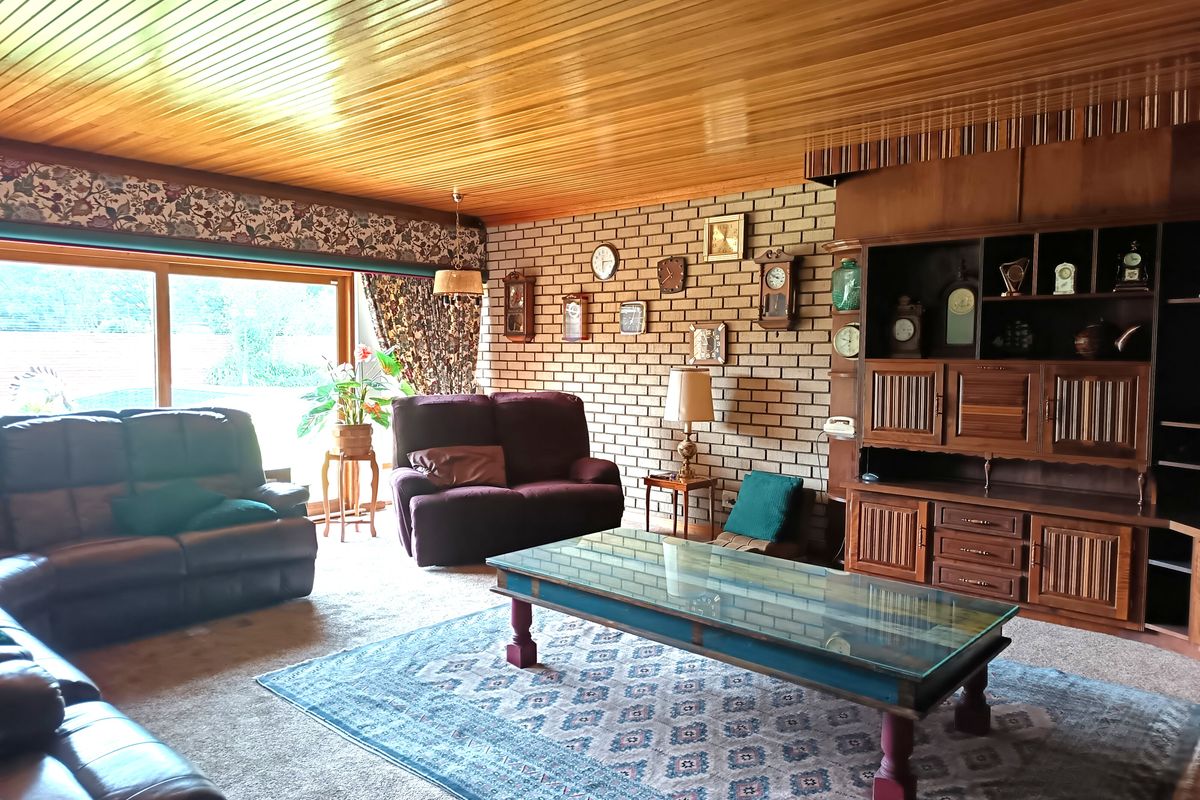Spacious living room featuring a prominent brick feature wall, built-in wooden cabinetry, and large sliding glass doors providing natural light and garden access.