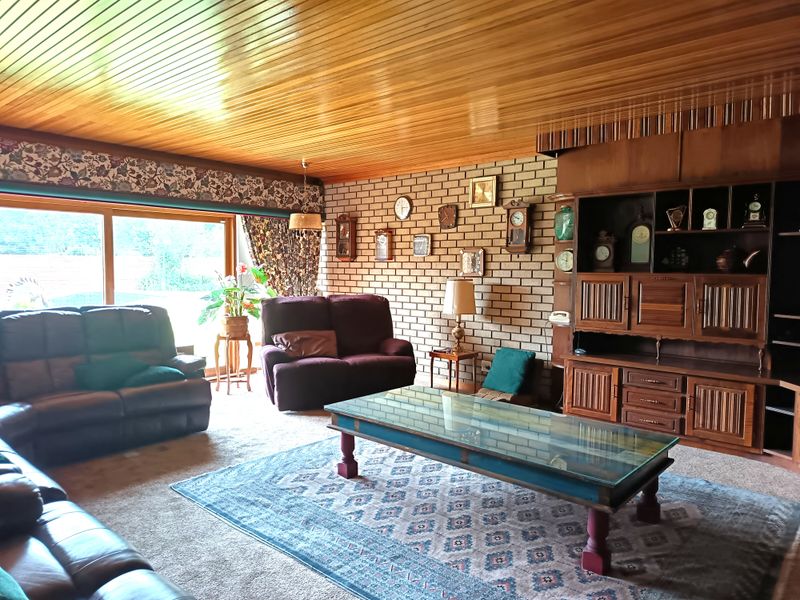 Spacious living room featuring a prominent brick feature wall, built-in wooden cabinetry, and large sliding glass doors providing natural light and garden access.