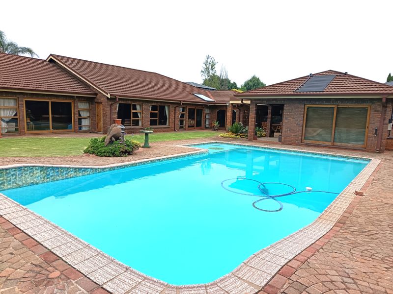 Spacious rear exterior featuring a large swimming pool, paved patio area, and well-maintained brick facade with sliding glass doors.