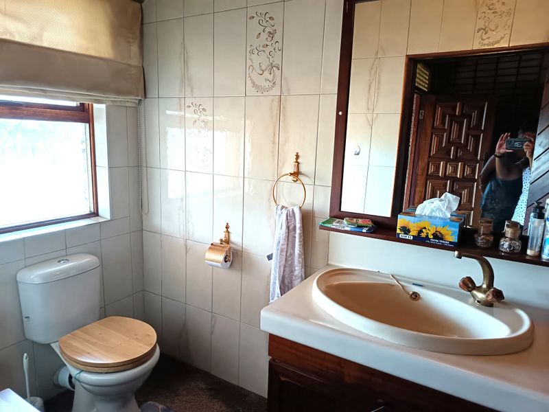 A functional bathroom featuring a vanity with a basin, a toilet, and wall-mounted fixtures, finished with classic ceramic tiling.