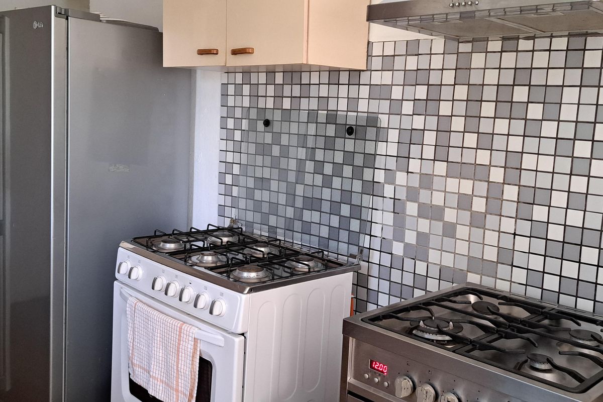 A functional kitchen area featuring a mosaic tile splashback, overhead cabinetry, and multiple gas stove units.