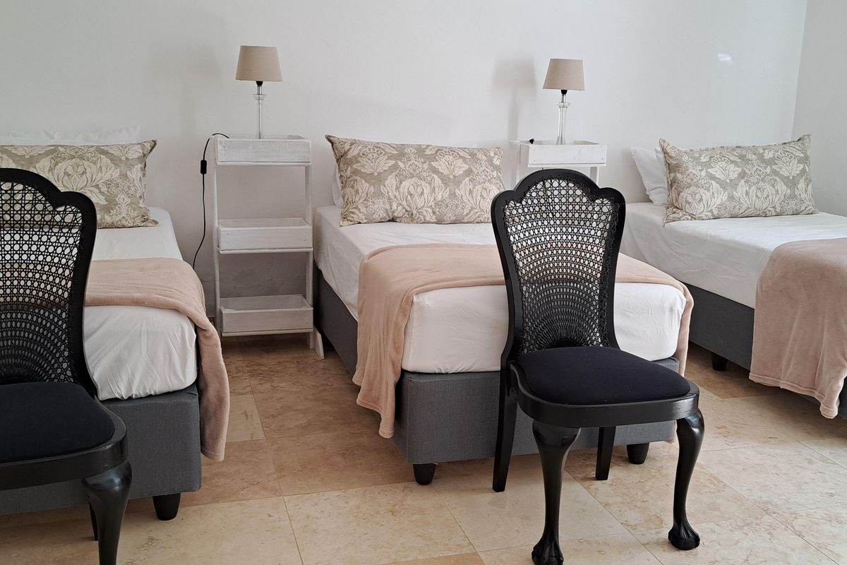 A bedroom featuring tiled flooring and space for multiple beds, suitable for guest accommodation or a shared living arrangement.