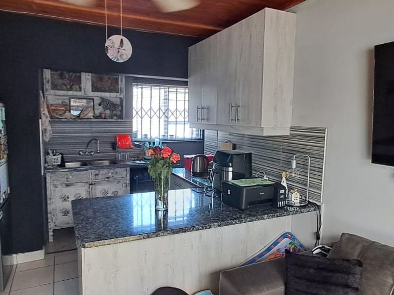 Open plan kitchen and living area featuring granite countertops, built-in cabinetry, and a timber ceiling, providing a functional layout for modern living.