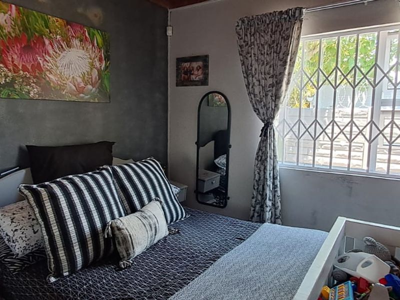 A bedroom featuring a window with a fitted security gate and a textured accent wall.